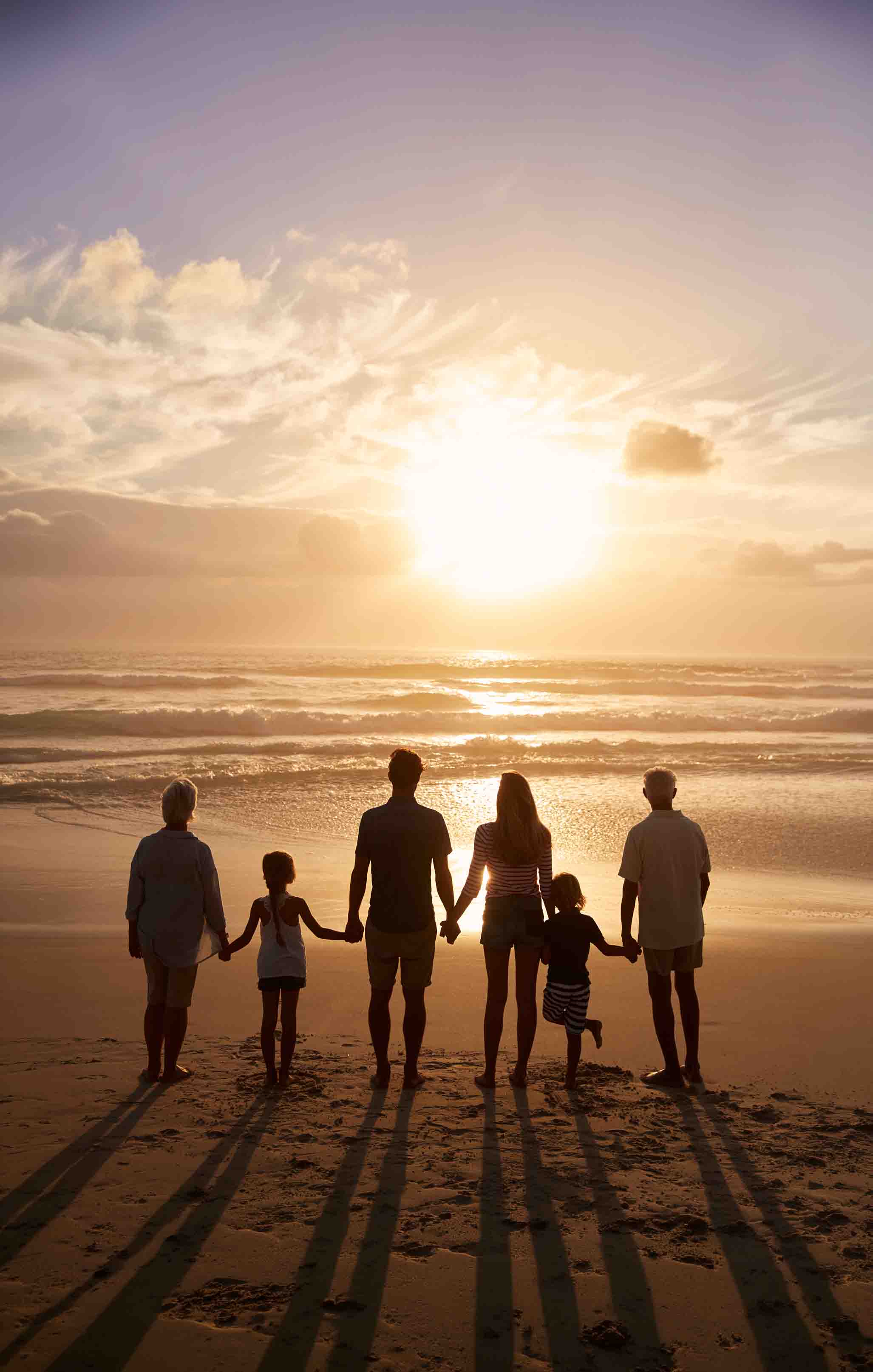 A multigenerational family silhouetted at sunset