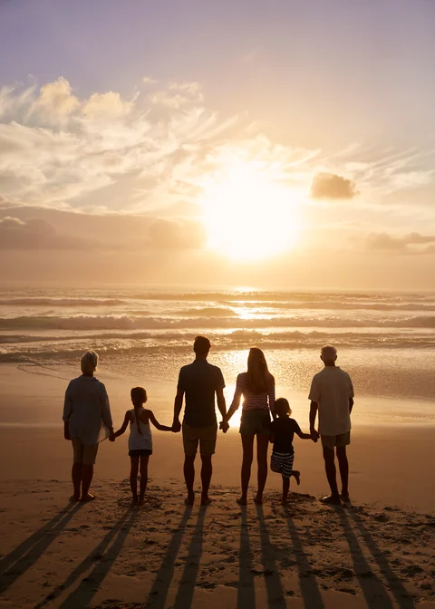 A multigenerational family silhouetted at sunset