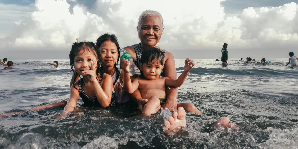 A grandmother and three children enjoying the ocean together
